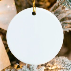 White round ornament hanging on a tree with blurred lights and greenery in the background
