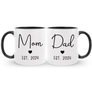 Two white mugs with black interior and handle, featuring 'Mom' and 'Dad' with heart symbols and 'Est. 2024' text.