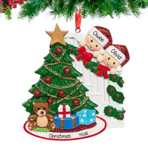 Personalized ornament of a smiling couple peeking from behind a decorated Christmas tree with names and 2025 engraved.